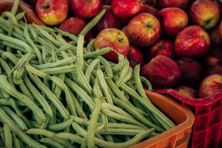 Close-up of fresh green beans and red apples at a local market.